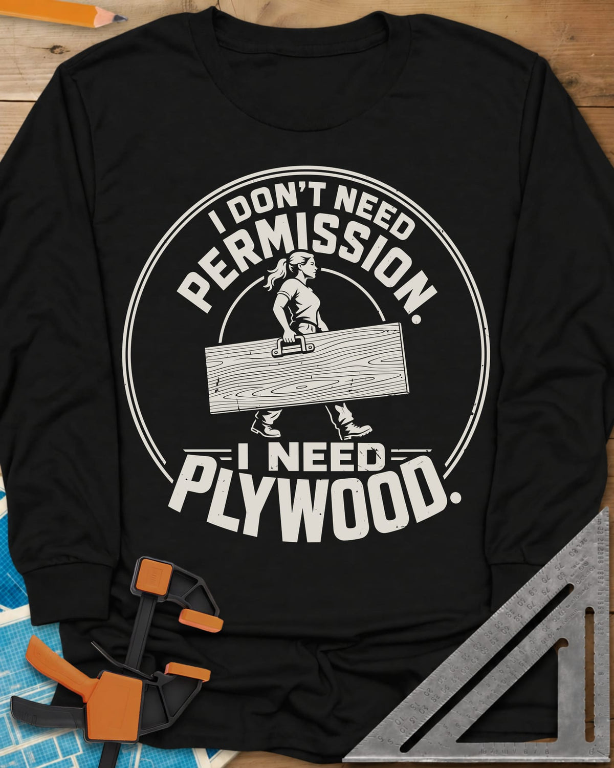 Need Plywood long sleeve shirt in Black, a woman with a ponytail carrying a plywood sheet in a round badge