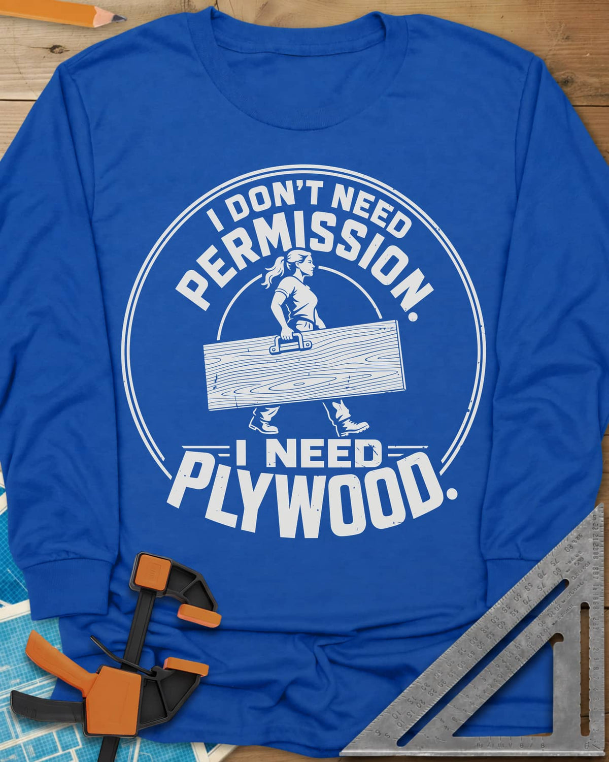 Need Plywood long sleeve shirt in Royal, a woman with a ponytail carrying a plywood sheet in a round badge