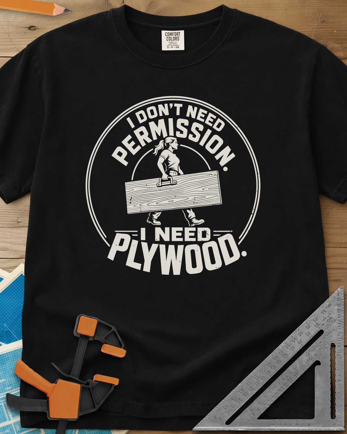 Need Plywood heavyweight tee in Black, a woman with a ponytail carrying a plywood sheet in a round badge