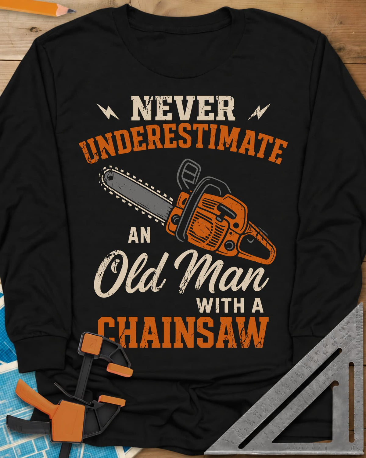 Never Underestimate an Old Man With a Chainsaw long sleeve shirt in Black, an orange chainsaw between lightning bolts and