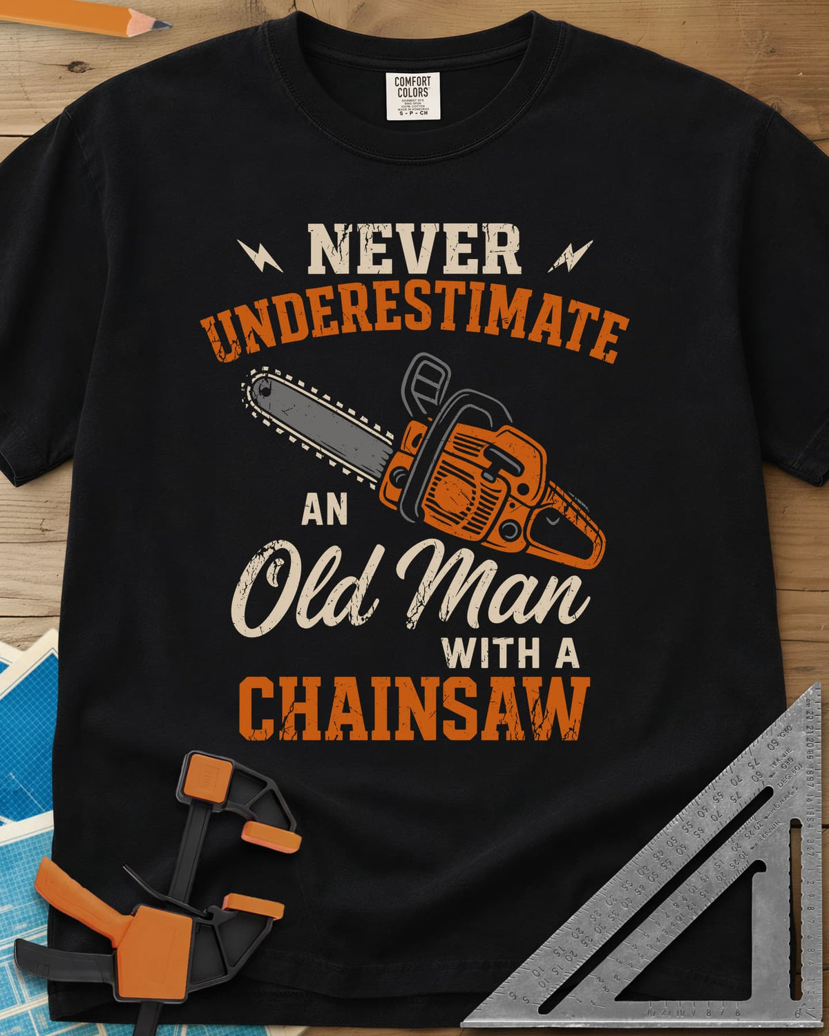 Never Underestimate an Old Man With a Chainsaw heavyweight tee in Black, an orange chainsaw between lightning bolts and