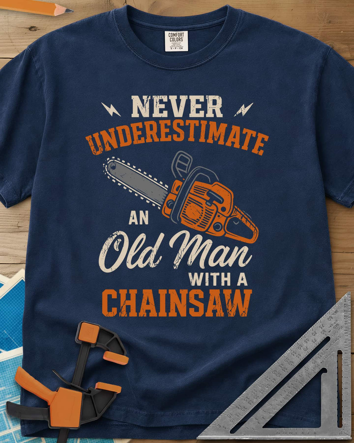 Never Underestimate an Old Man With a Chainsaw heavyweight tee in Navy, an orange chainsaw between lightning bolts and mixed