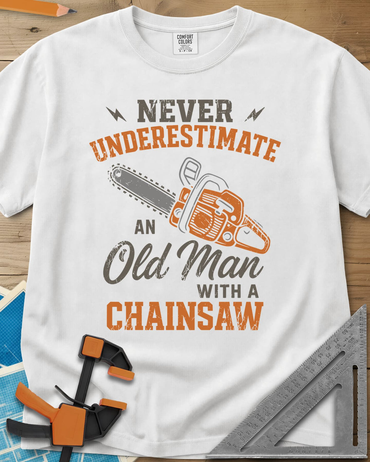 Never Underestimate an Old Man With a Chainsaw heavyweight tee in White, an orange chainsaw between lightning bolts and