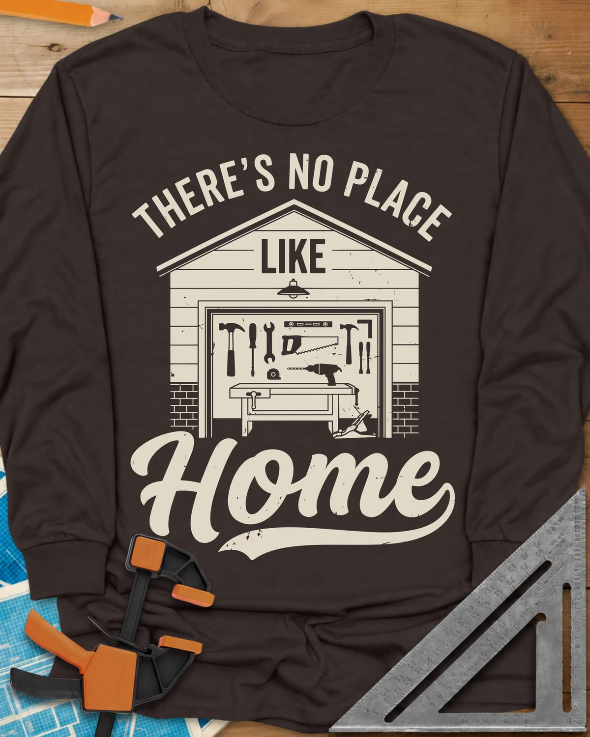 No Place Like Home long sleeve shirt in Dark Chocolate, a garage with its door up on a tool wall, above script Home