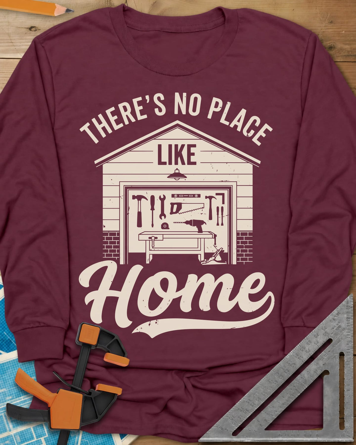 No Place Like Home long sleeve shirt in Maroon, a garage with its door up on a tool wall, above script Home