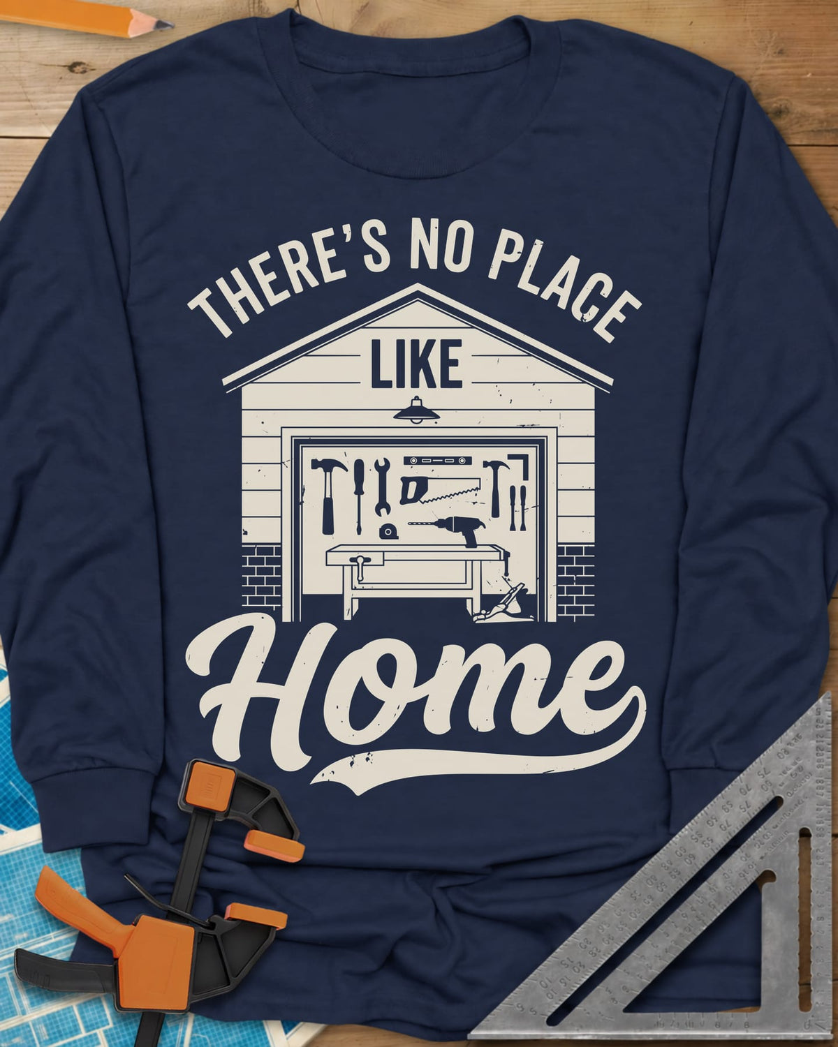 No Place Like Home long sleeve shirt in Navy, a garage with its door up on a tool wall, above script Home