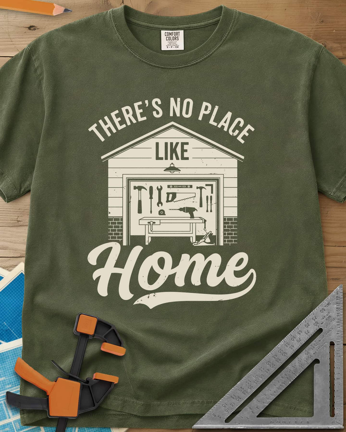No Place Like Home heavyweight tee in Hemp, a garage with its door up on a tool wall, above script Home