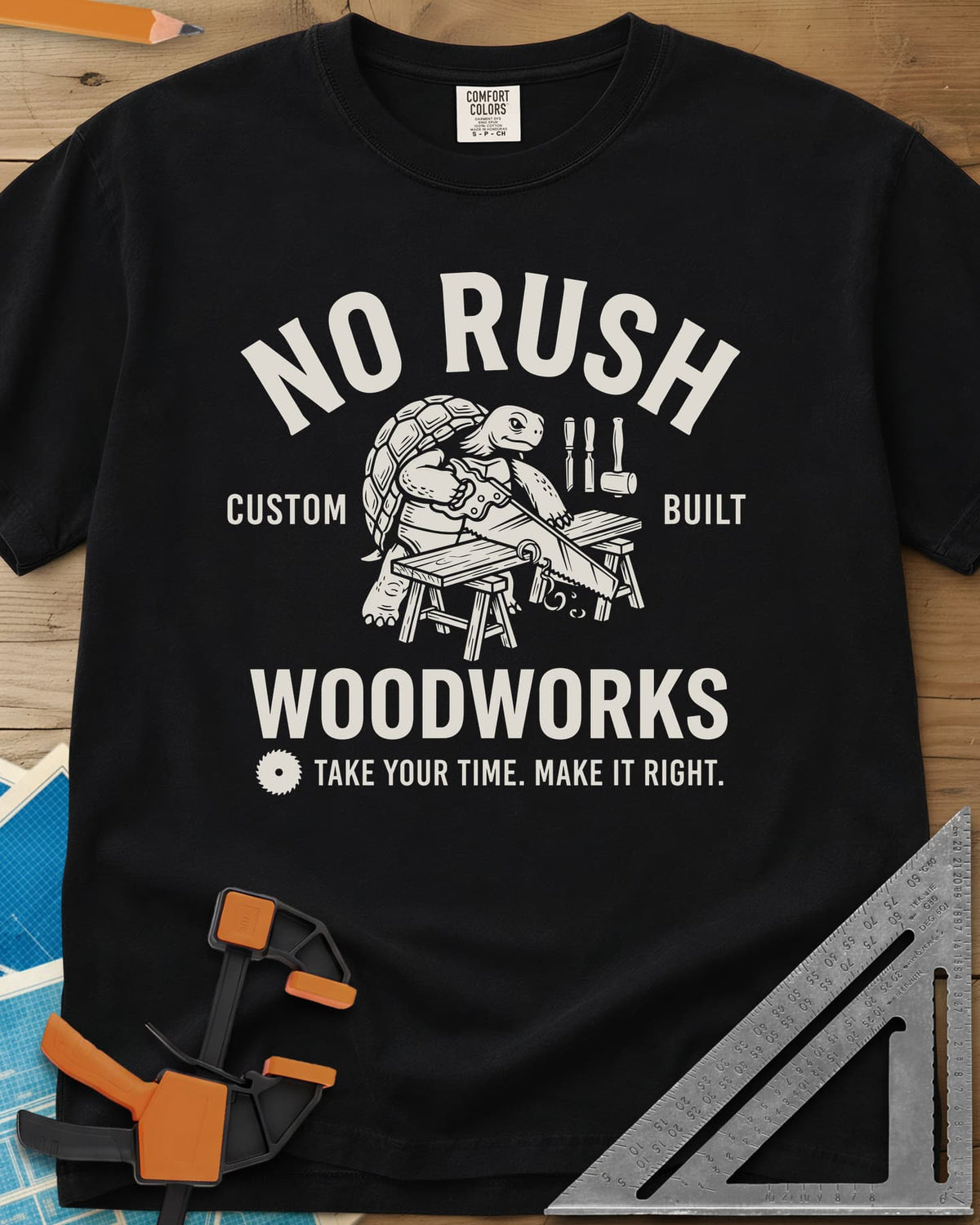 No Rush Woodworks heavyweight tee in Black, a tortoise sawing a board on sawhorses inside a woodshop badge