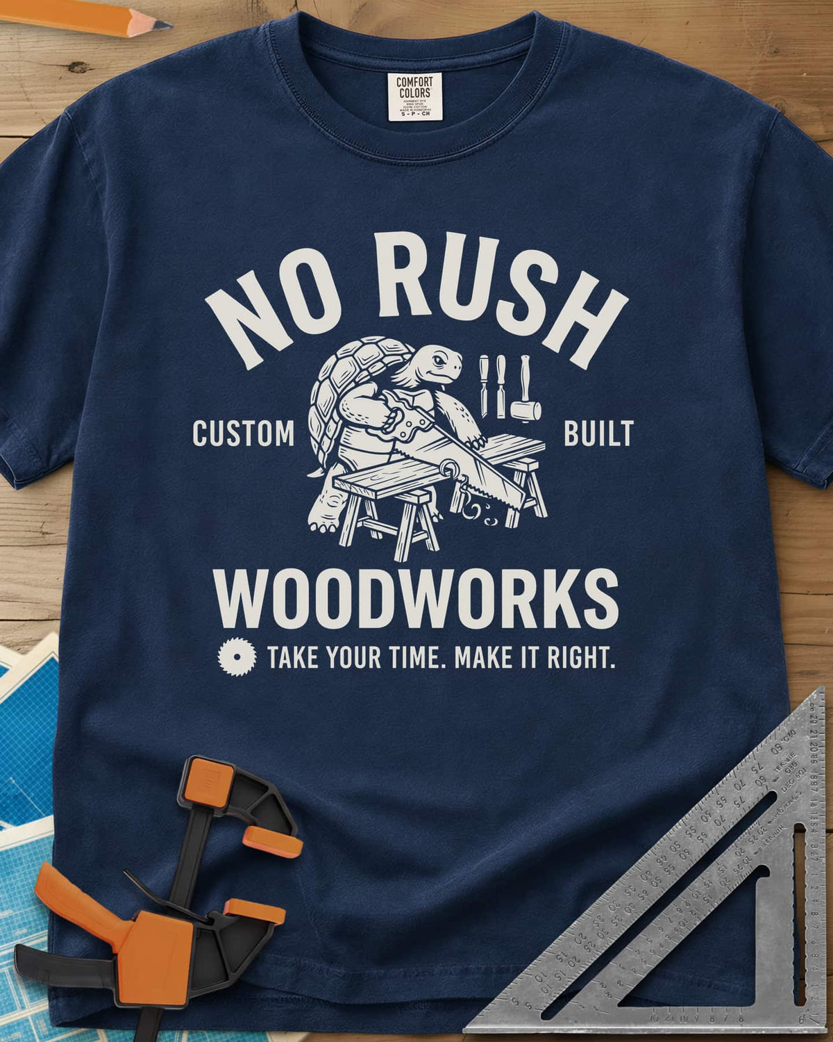 No Rush Woodworks heavyweight tee in Navy, a tortoise sawing a board on sawhorses inside a woodshop badge