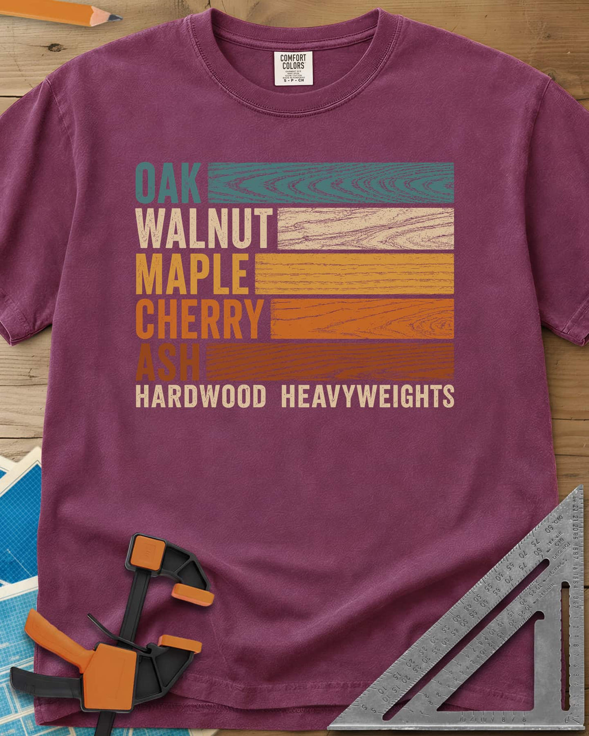 Oak Walnut Maple Cherry Ash heavyweight tee in Berry, five wood names beside strips of their own grain in retro colors