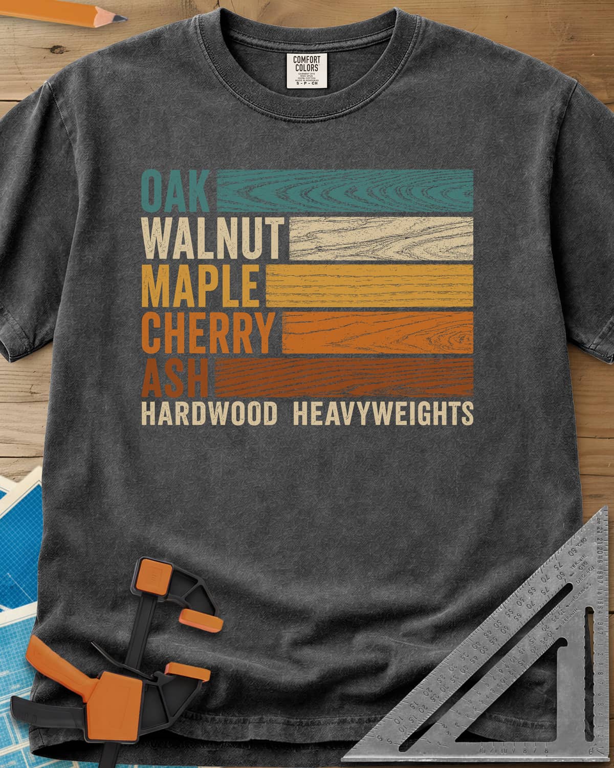 Oak Walnut Maple Cherry Ash heavyweight tee in Pepper, five wood names beside strips of their own grain in retro colors