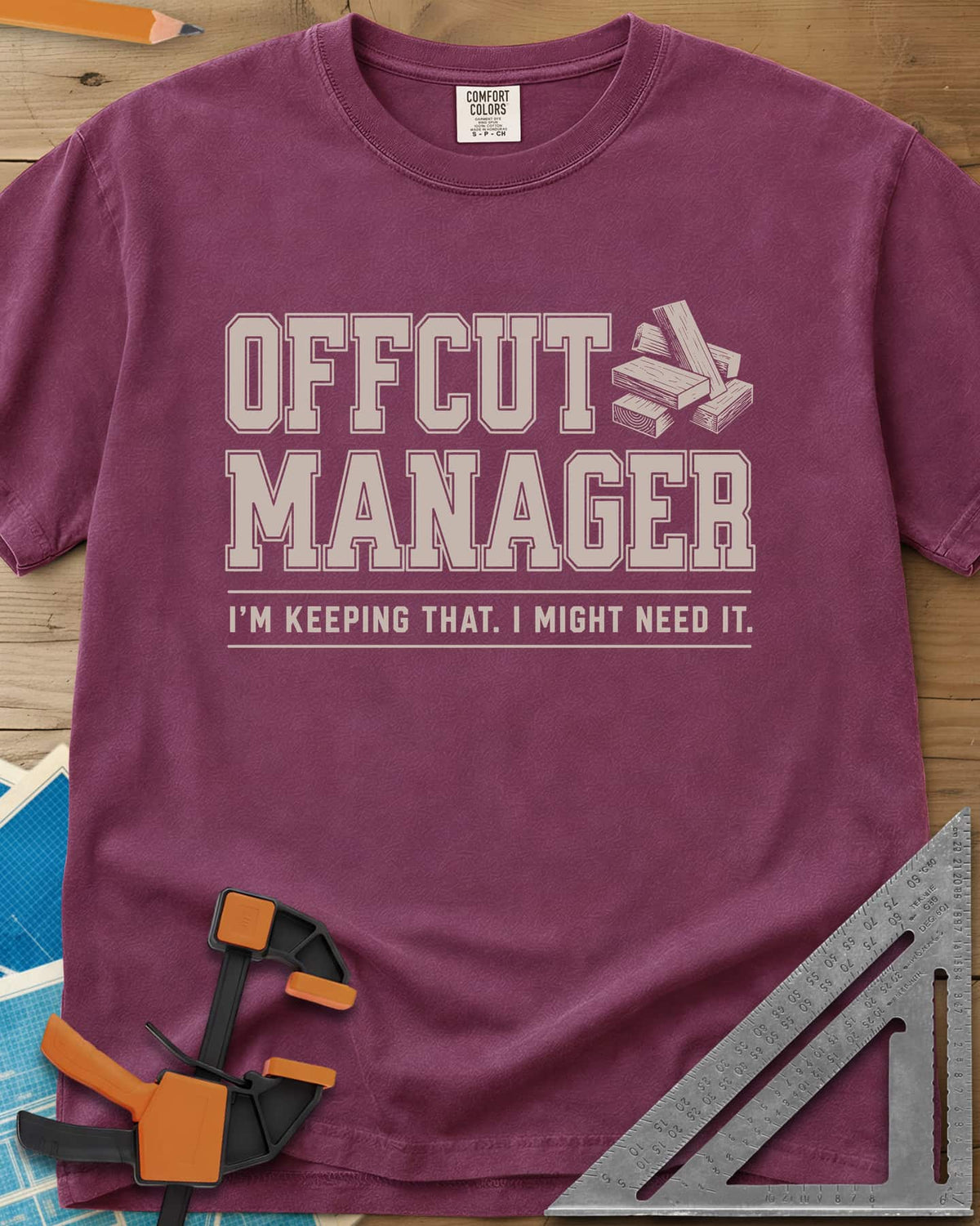 Offcut Manager heavyweight tee in Berry, varsity block lettering beside a little stack of wood offcuts