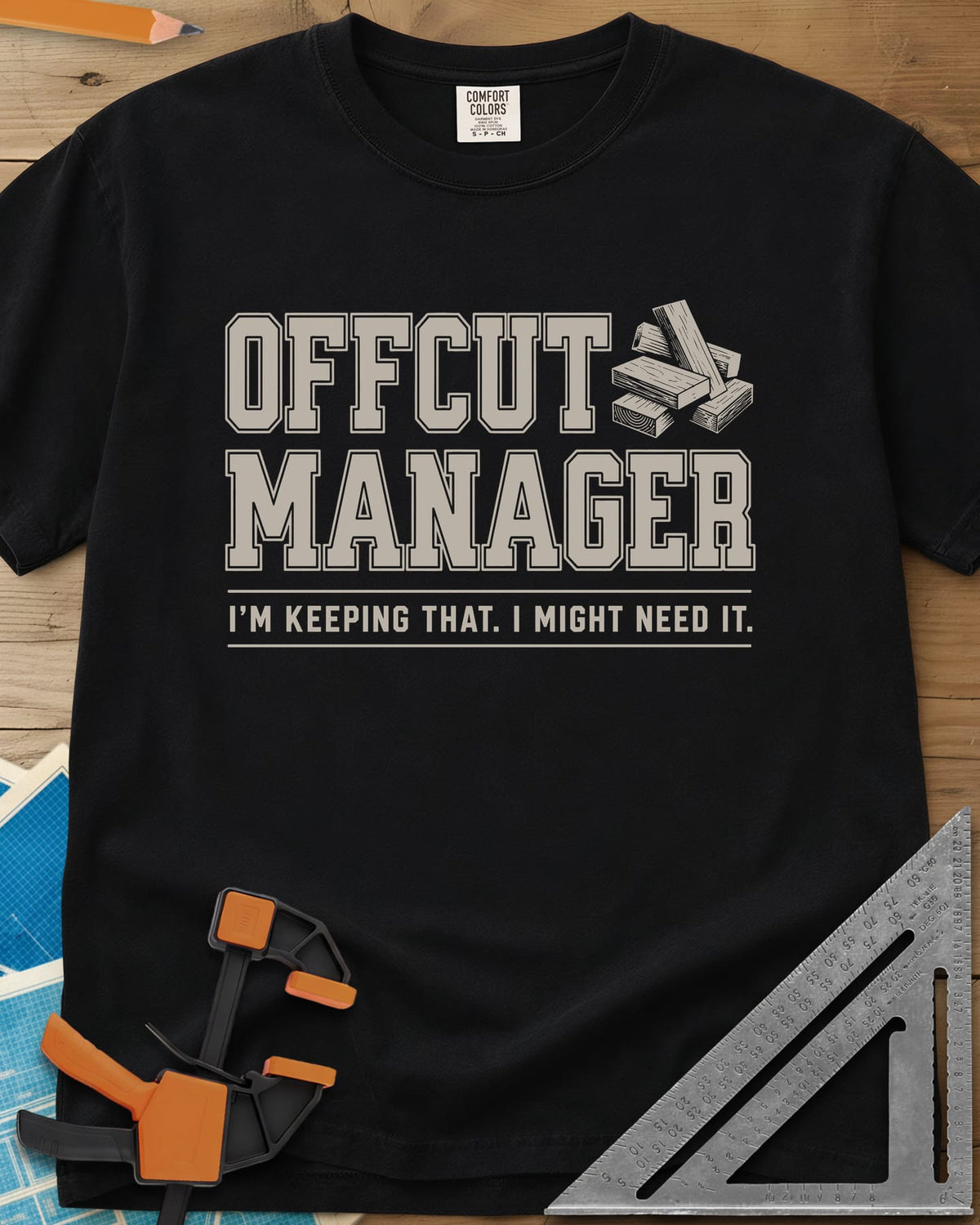 Offcut Manager heavyweight tee in Black, varsity block lettering beside a little stack of wood offcuts