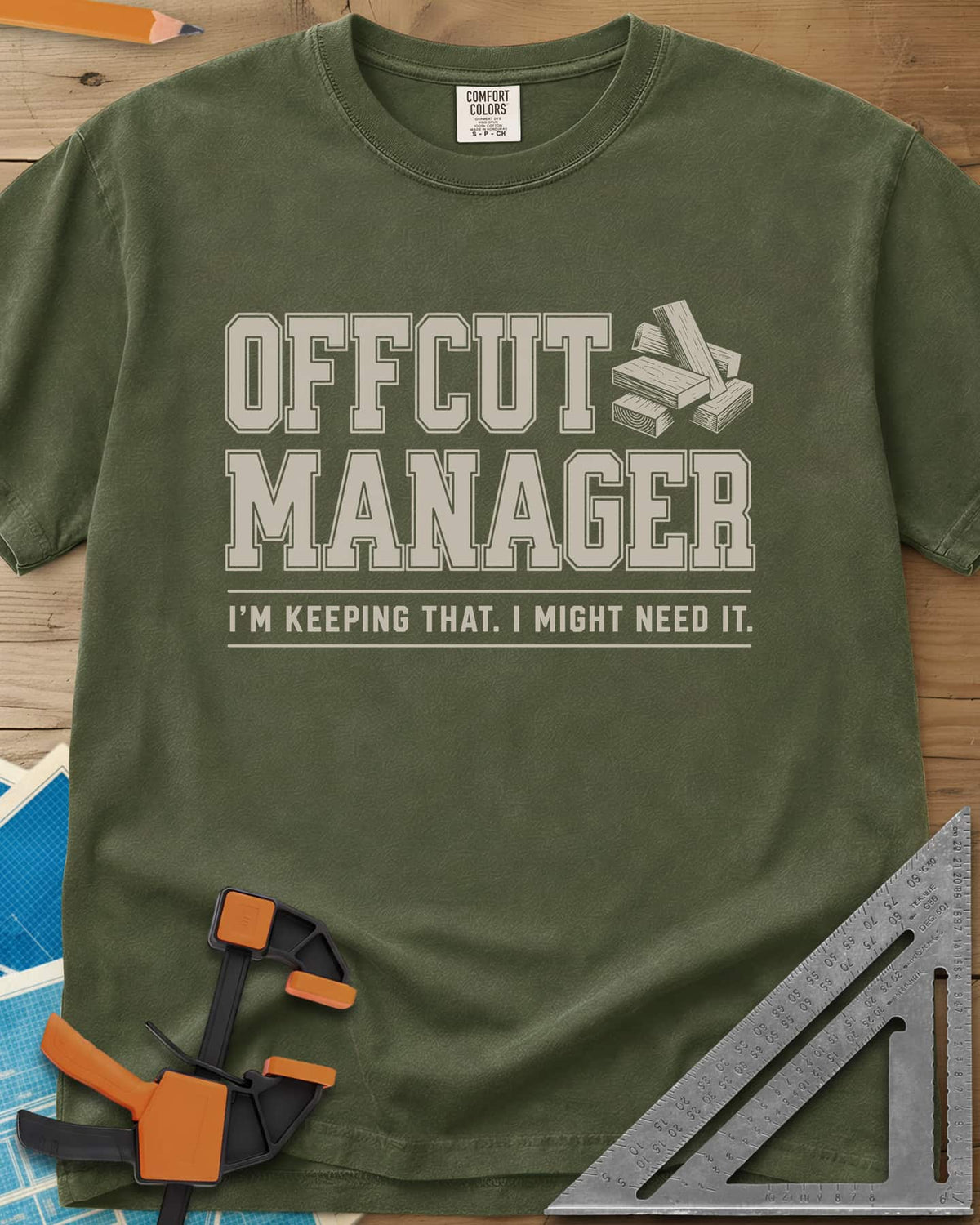 Offcut Manager heavyweight tee in Hemp, varsity block lettering beside a little stack of wood offcuts