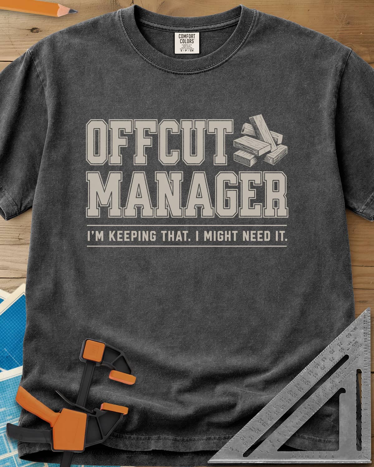 Offcut Manager heavyweight tee in Pepper, varsity block lettering beside a little stack of wood offcuts