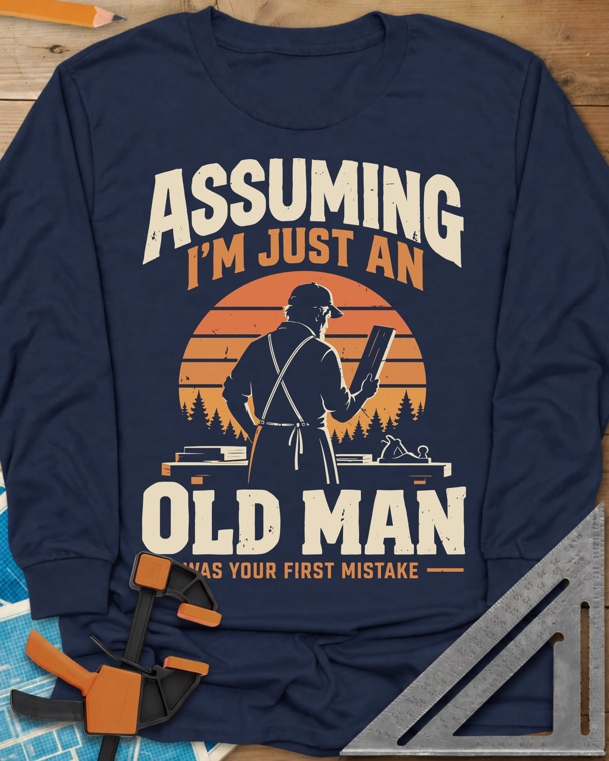 Old Man Mistake long sleeve shirt in Navy, a woodworker in an apron holding a board before a striped sunset