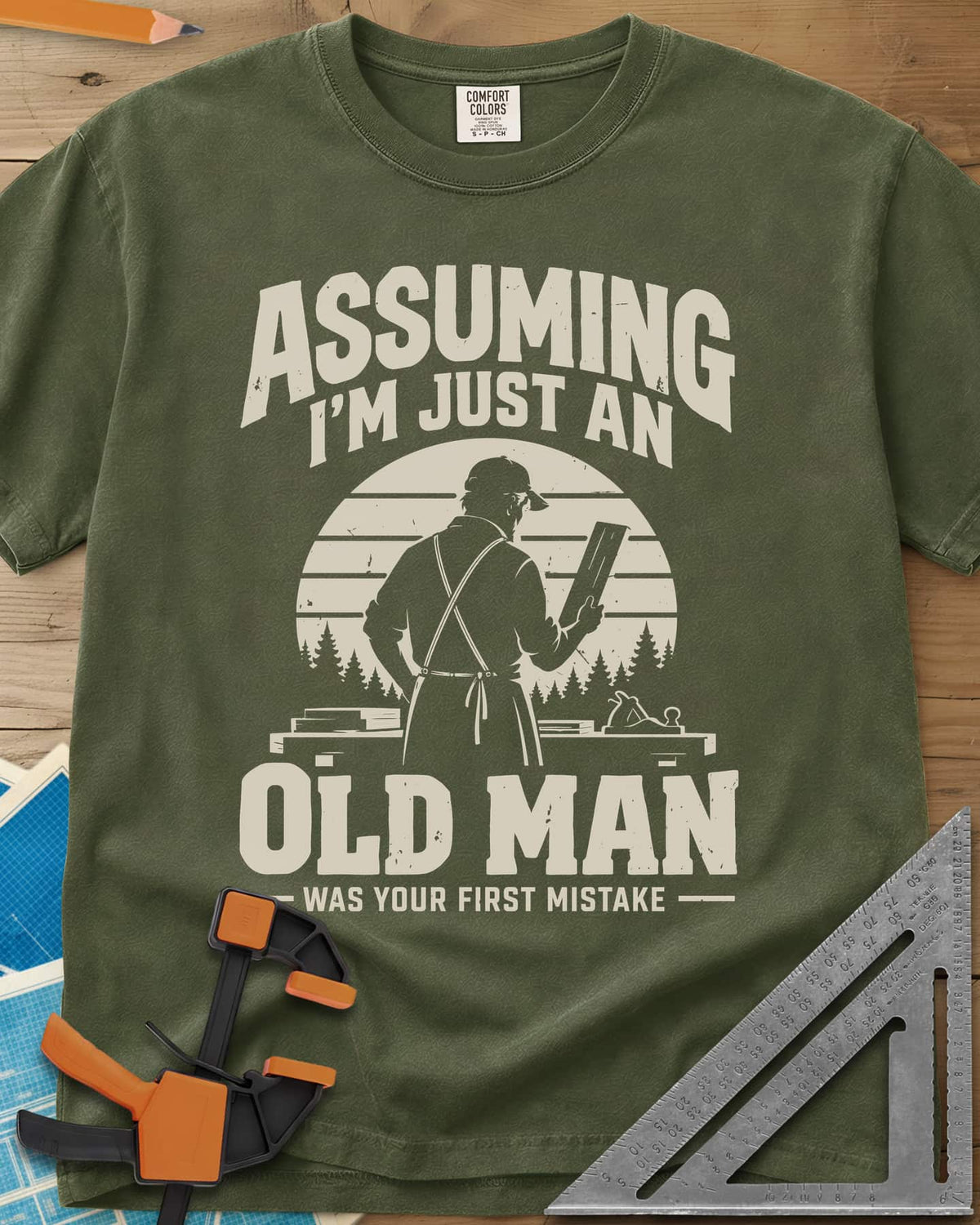 Old Man Mistake heavyweight tee in Hemp, a woodworker in an apron holding a board before a striped sunset
