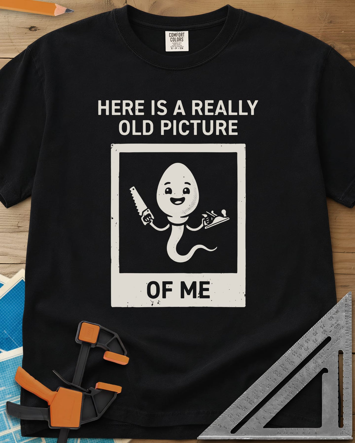 Old Picture heavyweight tee in Black, a smiling cartoon figure with a long tail holding a saw and a plane
