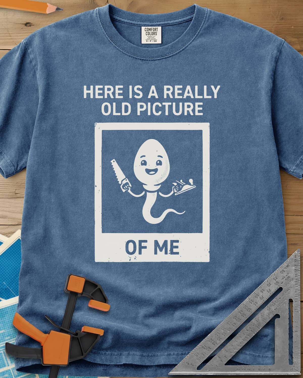 Old Picture heavyweight tee in Blue Jean, a smiling cartoon figure with a long tail holding a saw and a plane