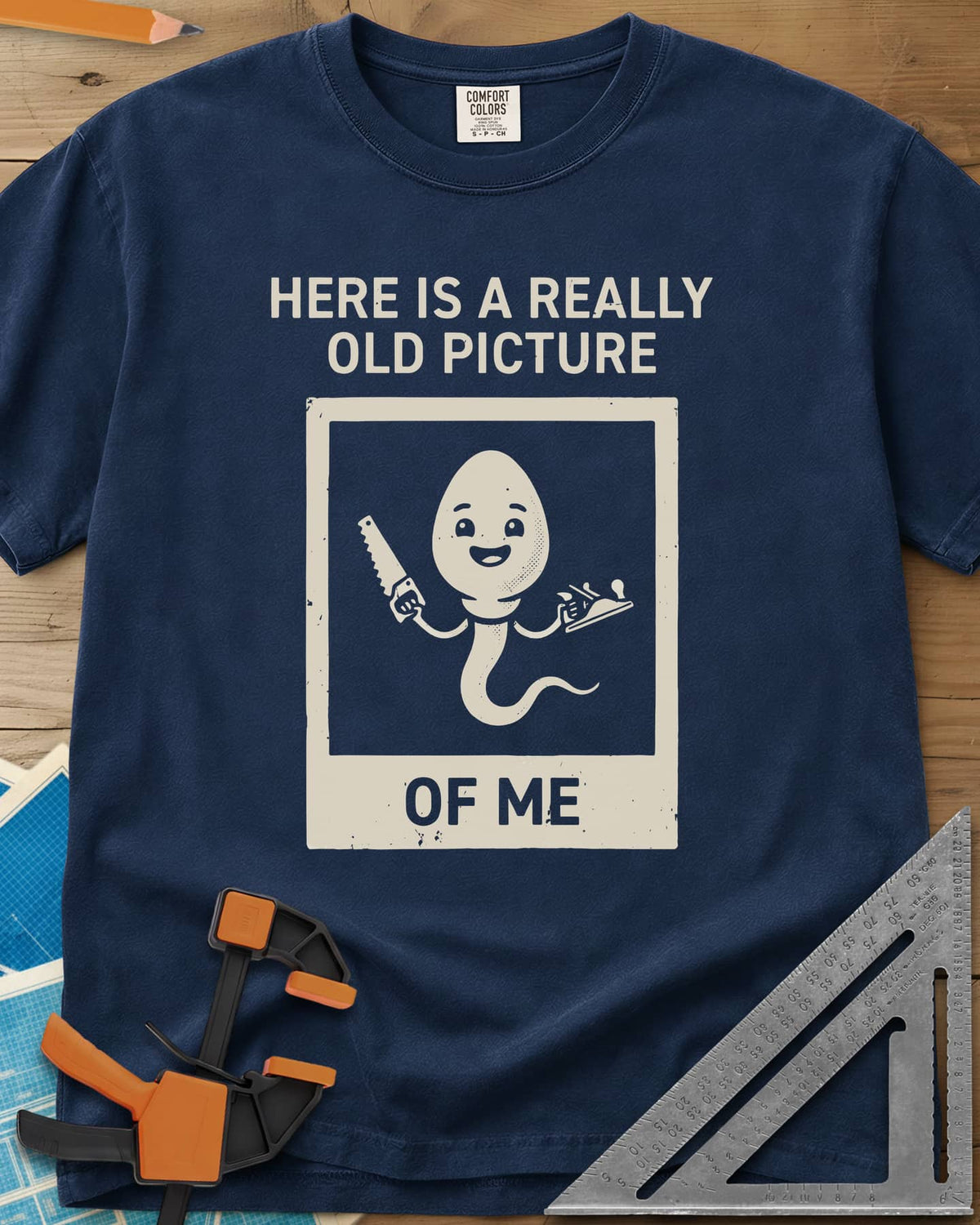 Old Picture heavyweight tee in Navy, a smiling cartoon figure with a long tail holding a saw and a plane