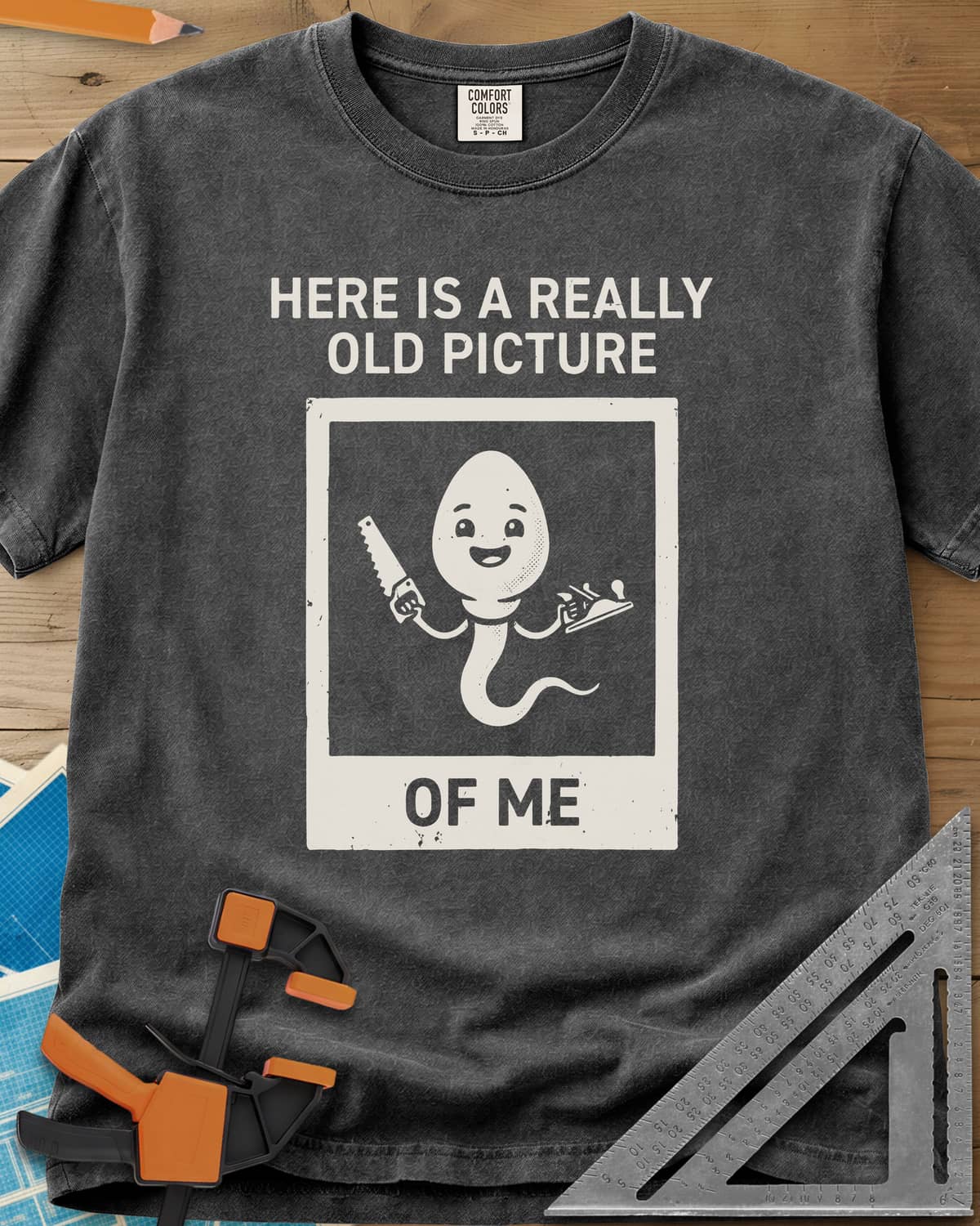 Old Picture heavyweight tee in Pepper, a smiling cartoon figure with a long tail holding a saw and a plane