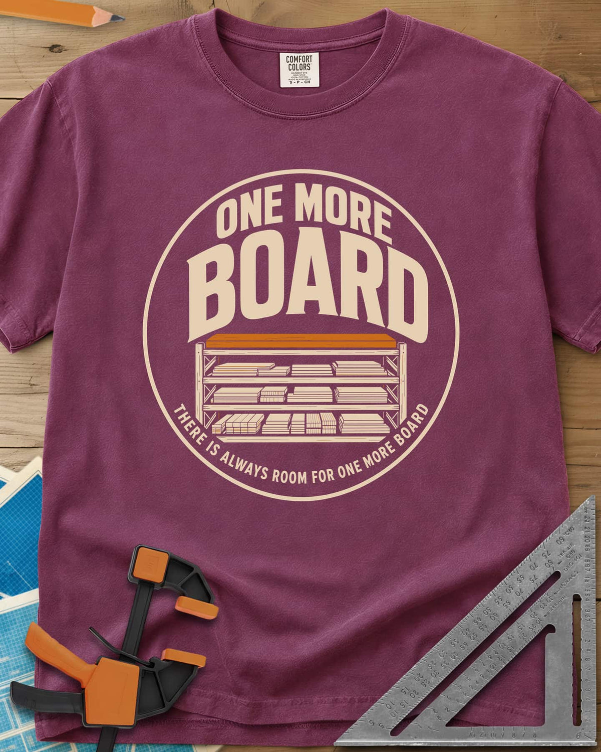 One More Board heavyweight tee in Berry, a round badge with a rack of stacked lumber
