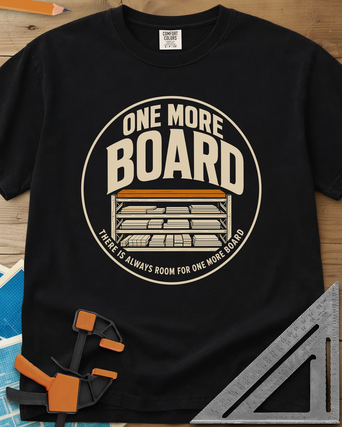 One More Board heavyweight tee in Black, a round badge with a rack of stacked lumber