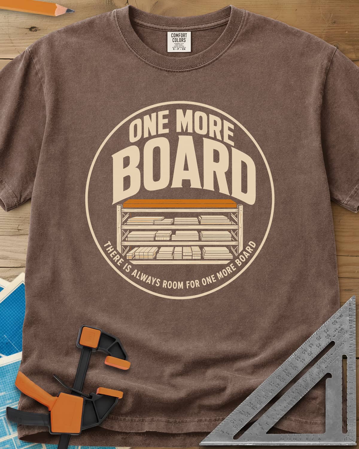 One More Board heavyweight tee in Espresso, a round badge with a rack of stacked lumber