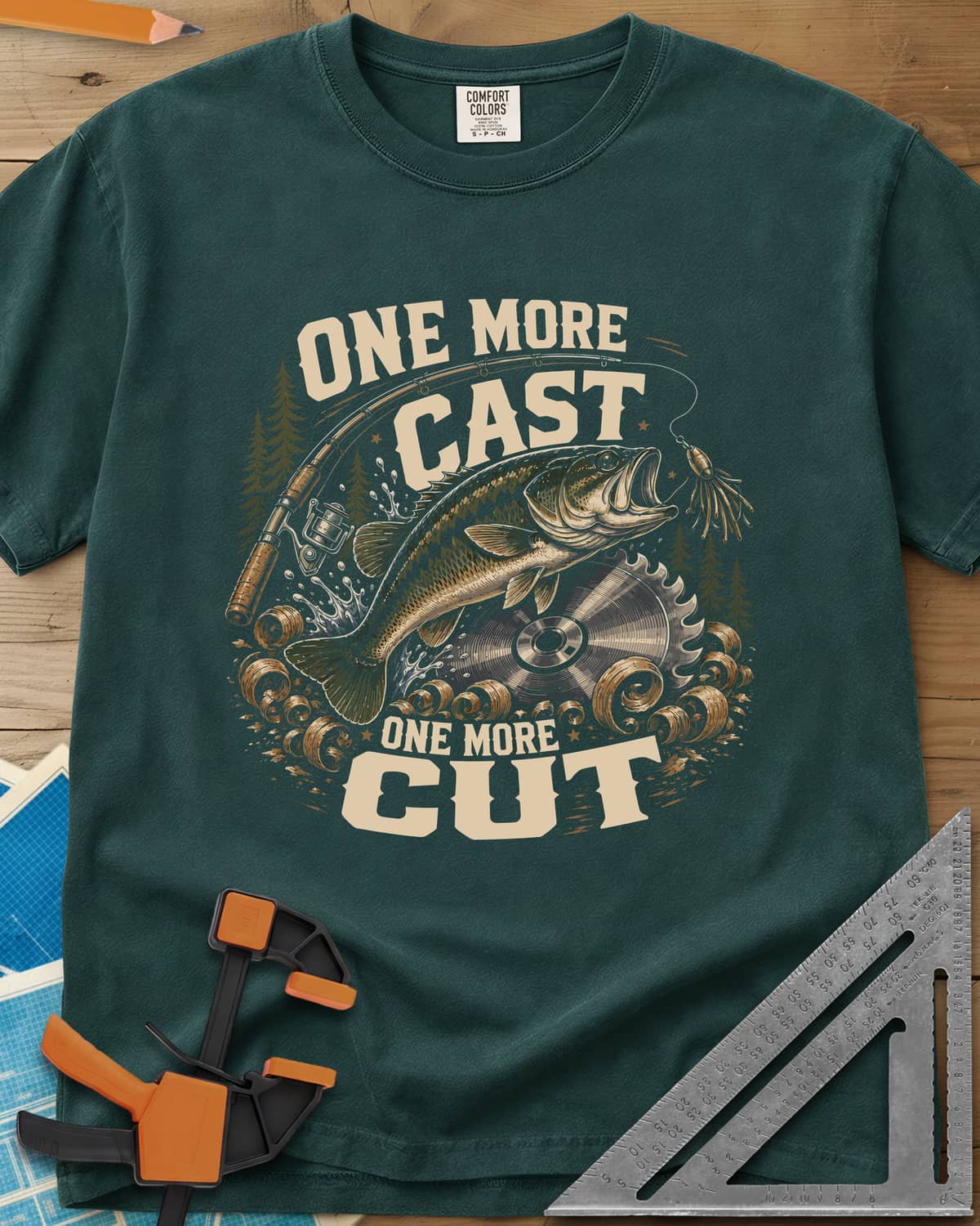One More Cast One More Cut heavyweight tee in Blue Spruce, a leaping bass, saw blade, fishing rod and wood curls