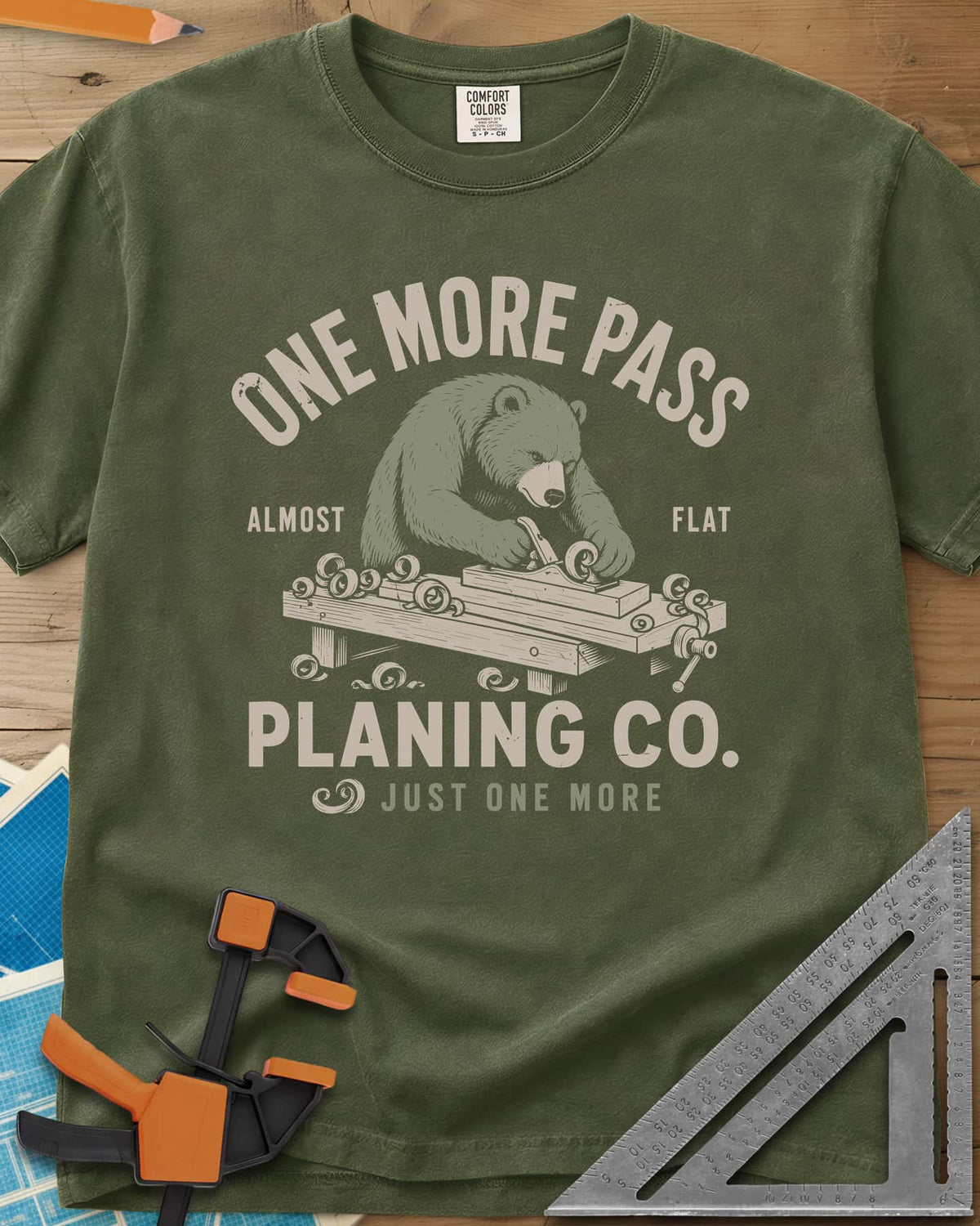 One More Pass heavyweight tee in Hemp, a blue bear hand-planing a board at a workbench, shavings curling