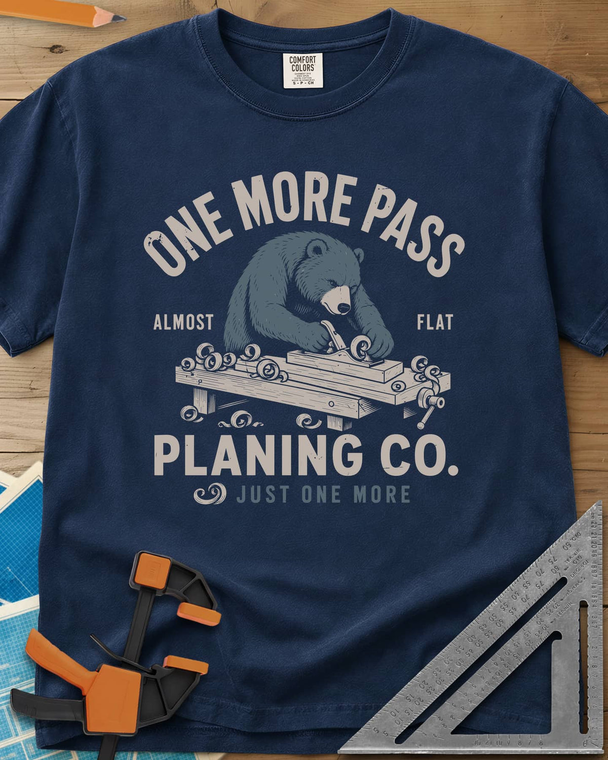 One More Pass heavyweight tee in Navy, a blue bear hand-planing a board at a workbench, shavings curling