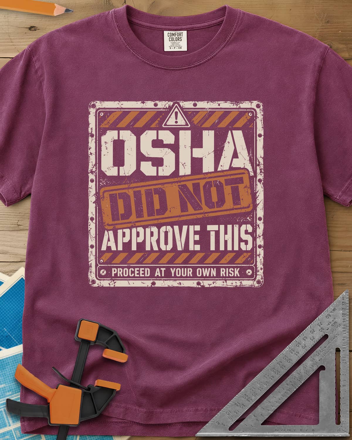 OSHA Not Approved heavyweight tee in Berry, a worn warning sign with hazard stripes and a DID NOT stamp
