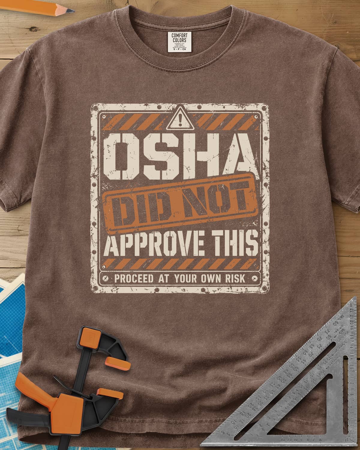 OSHA Not Approved heavyweight tee in Espresso, a worn warning sign with hazard stripes and a DID NOT stamp