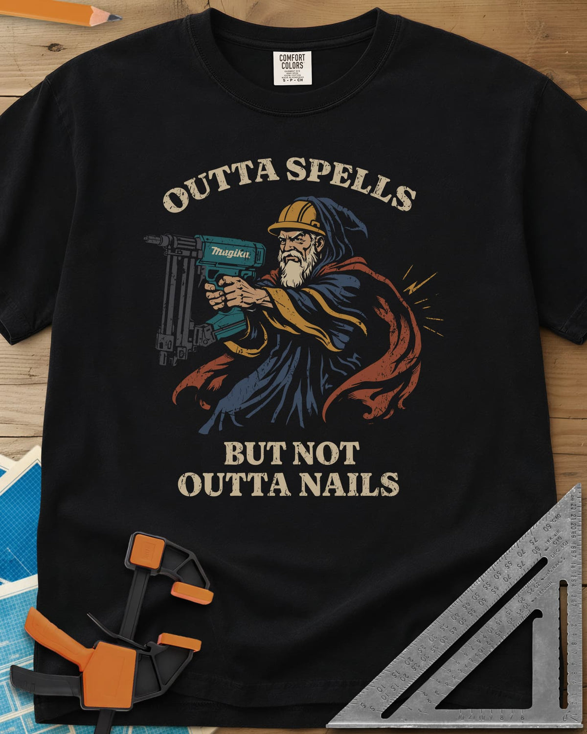Outta Spells But Not Outta Nails heavyweight tee in Black, a bearded wizard in a hard hat aiming a teal nail gun