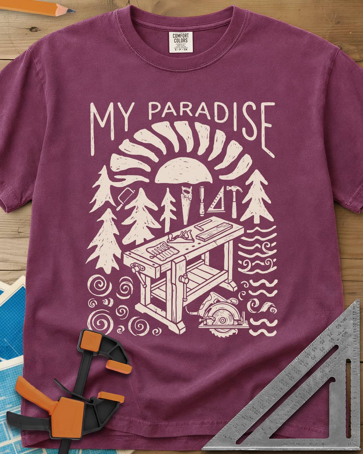 Paradise Workshop heavyweight tee in Berry, linocut sun, pines, hand tools and a workbench with a plane