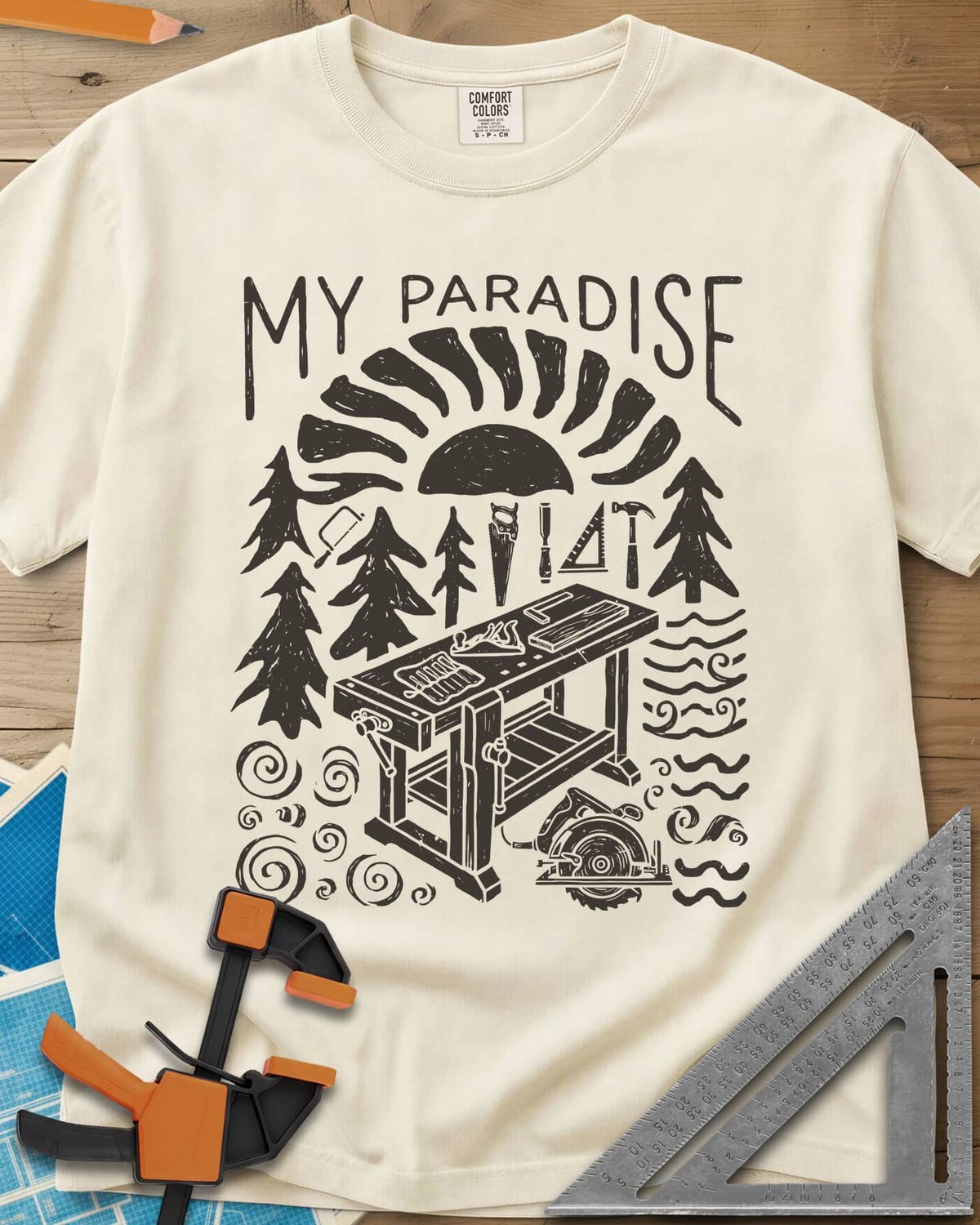 Paradise Workshop heavyweight tee in Ivory, linocut sun, pines, hand tools and a workbench with a plane