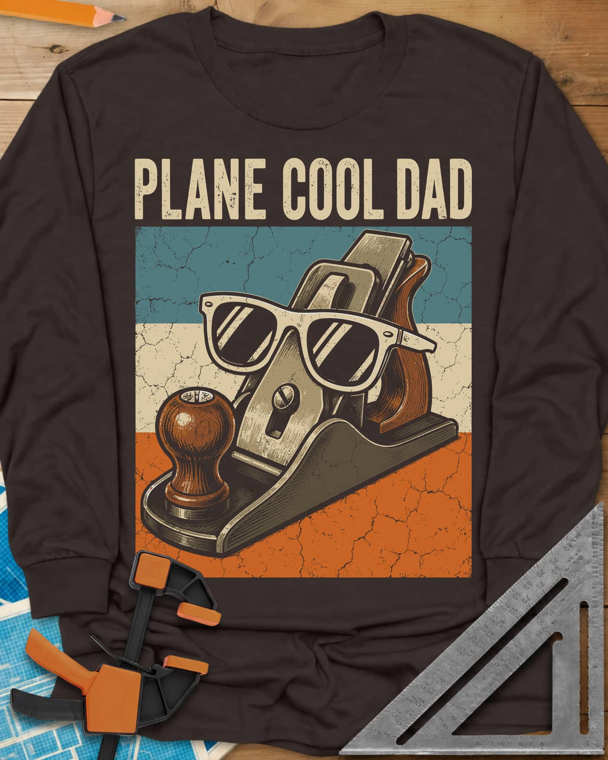 Plane Cool Dad long sleeve shirt in Dark Chocolate, a hand plane in white sunglasses on a retro striped panel