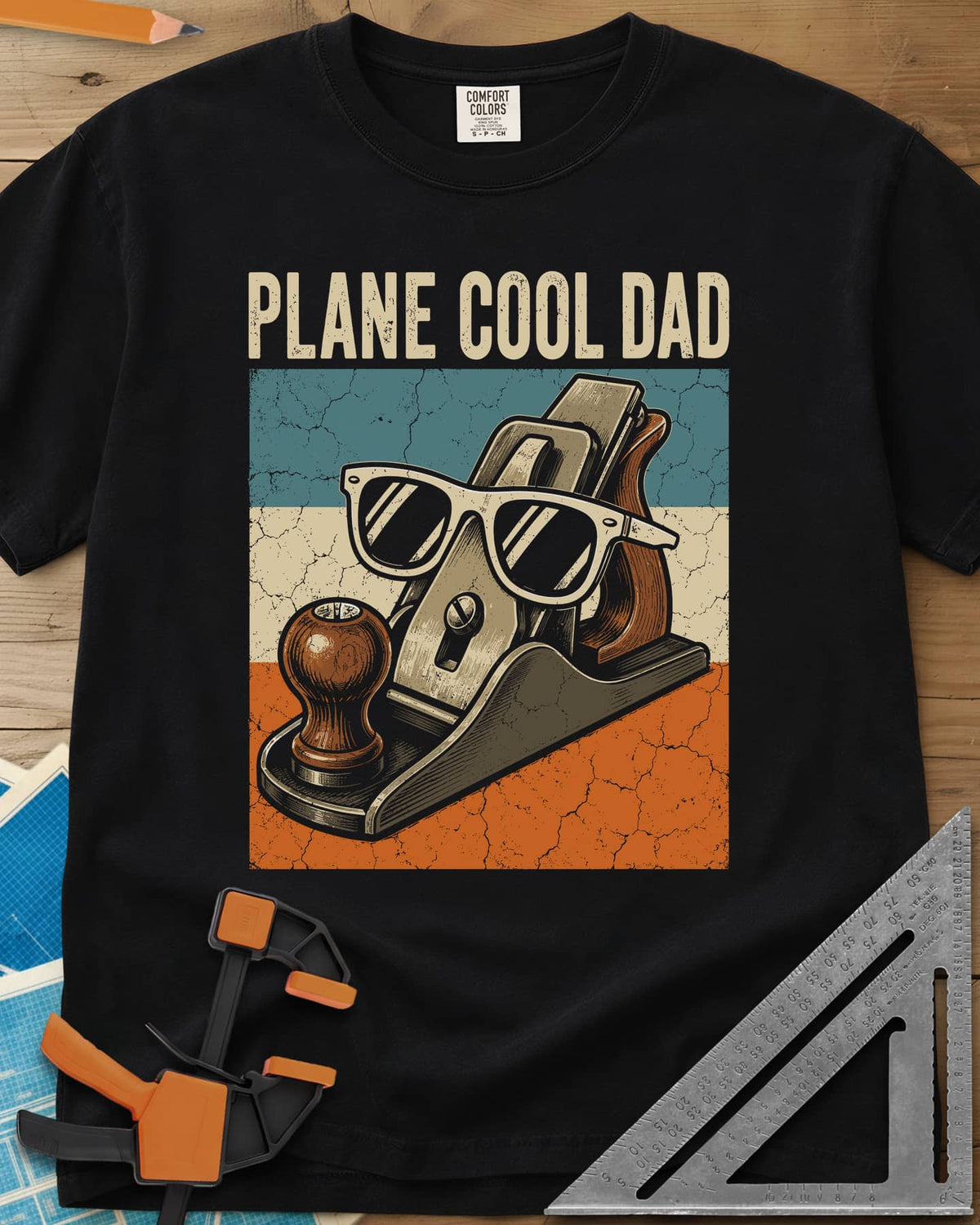 Plane Cool Dad heavyweight tee in Black, a hand plane in white sunglasses on a retro striped panel