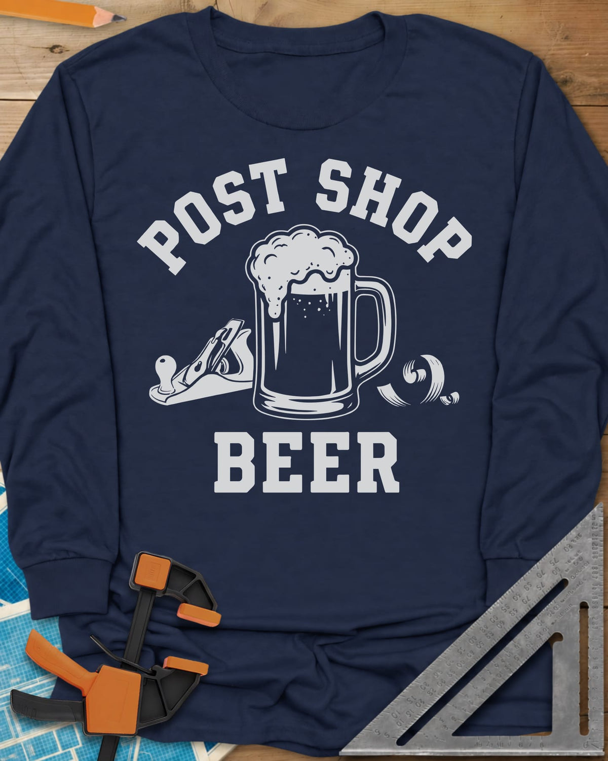 Post Shop Beer Woodworking long sleeve shirt in Navy, a frothy beer mug flanked by a hand plane and a wood shaving