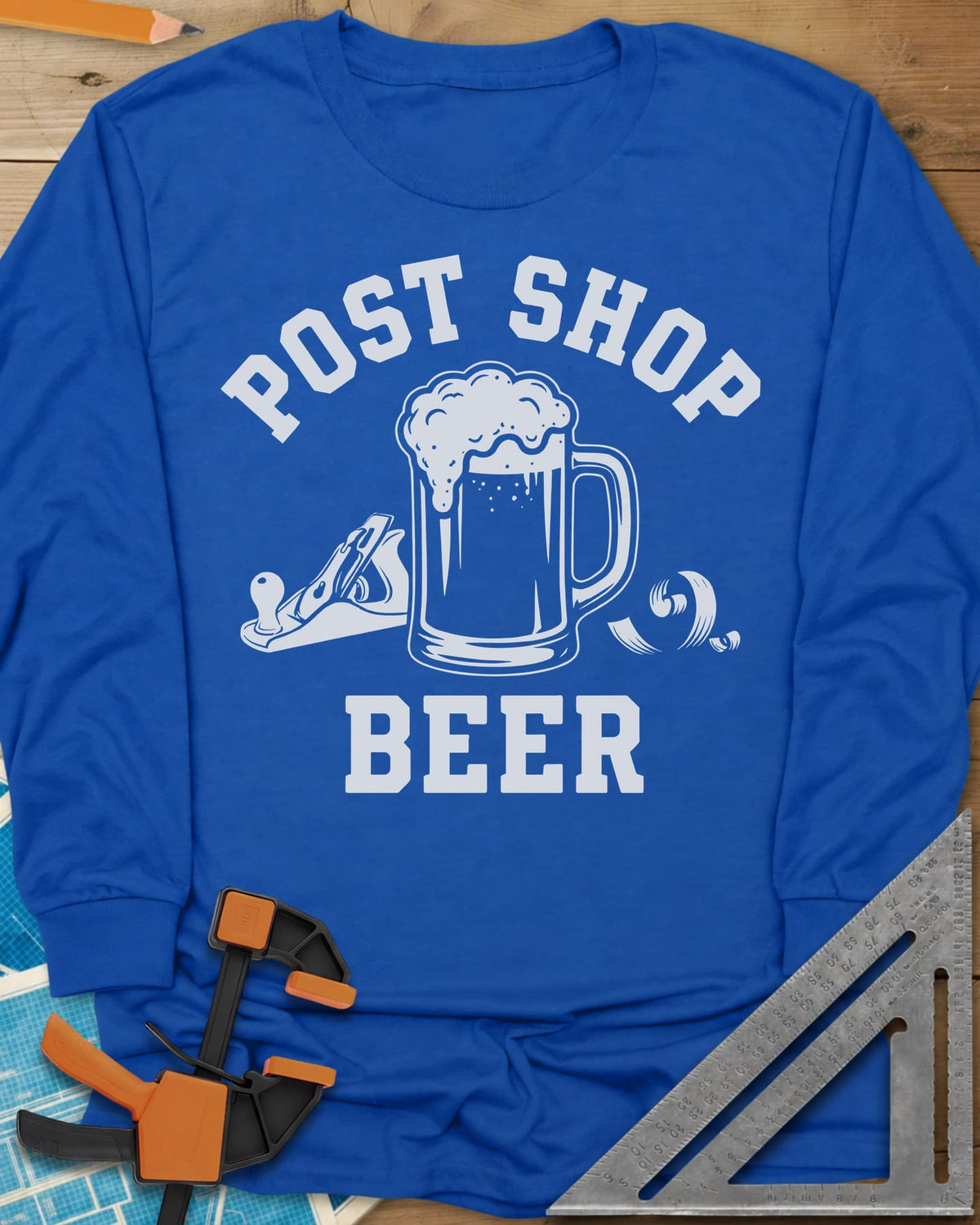 Post Shop Beer Woodworking long sleeve shirt in Royal, a frothy beer mug flanked by a hand plane and a wood shaving
