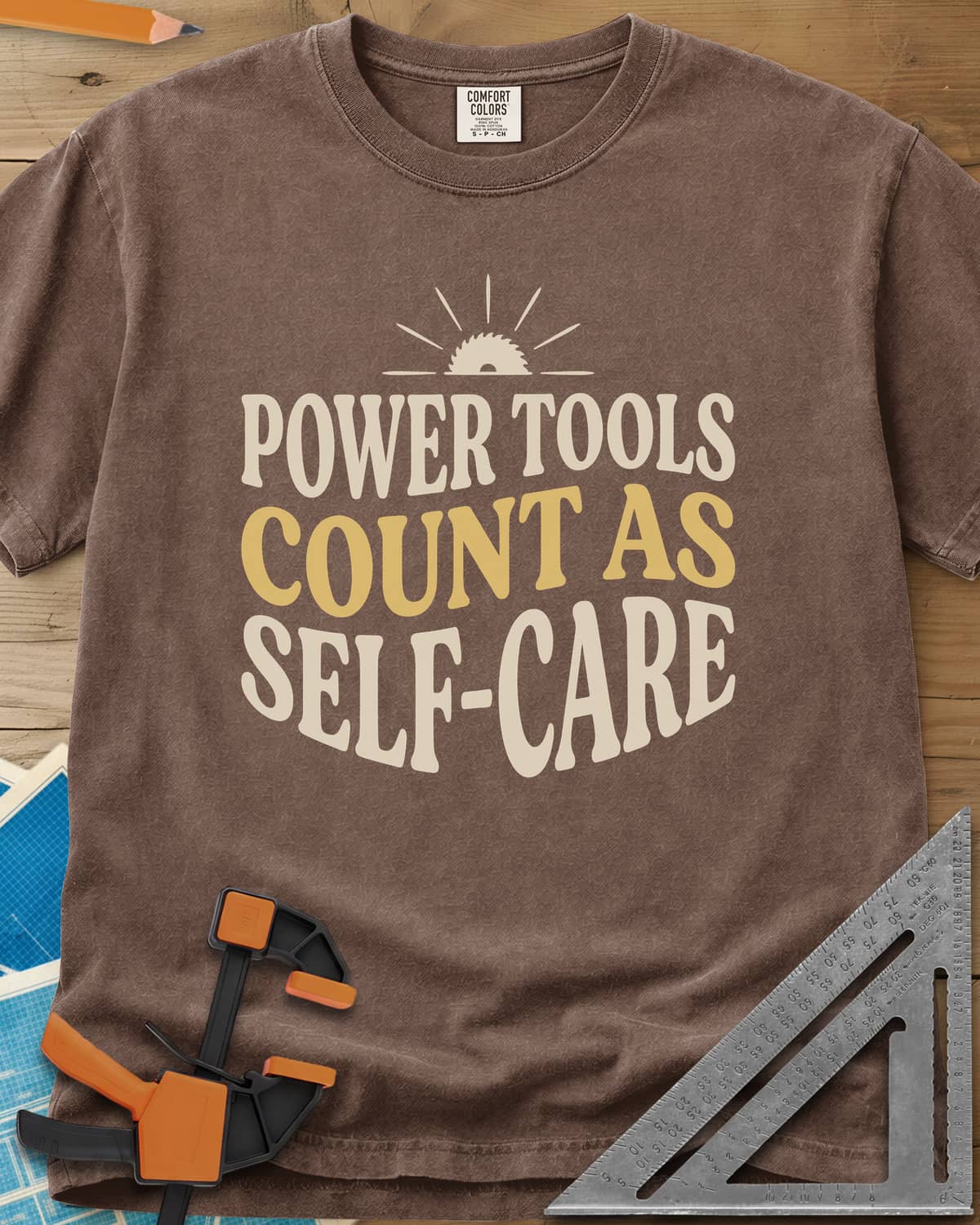 Power Tools Count As Self-Care heavyweight tee in Espresso, wavy stacked lettering under a half saw blade rising like a sun