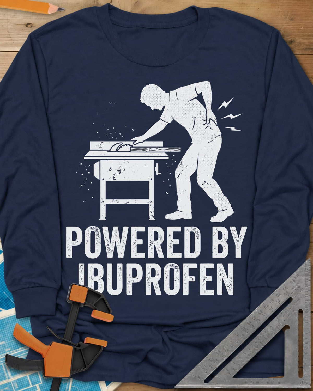 Powered By Ibuprofen long sleeve shirt in Navy, a man at a table saw with a hand on his sore back