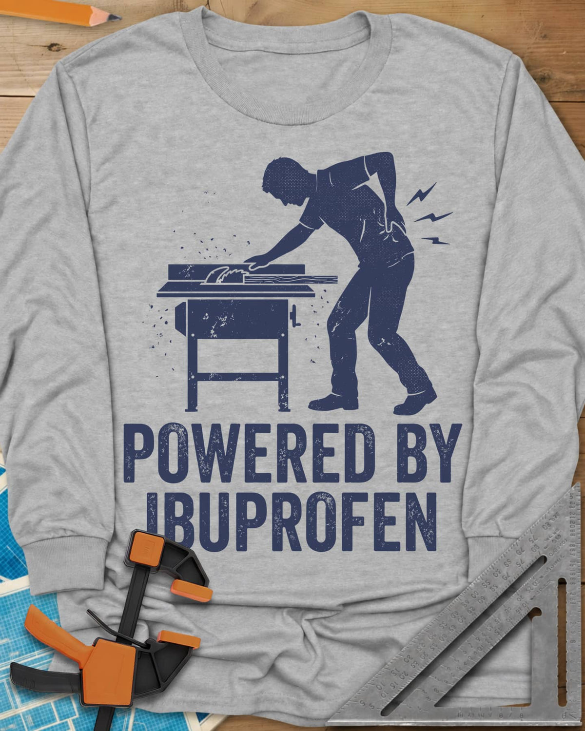 Powered By Ibuprofen long sleeve shirt in Sport Grey, a man at a table saw with a hand on his sore back