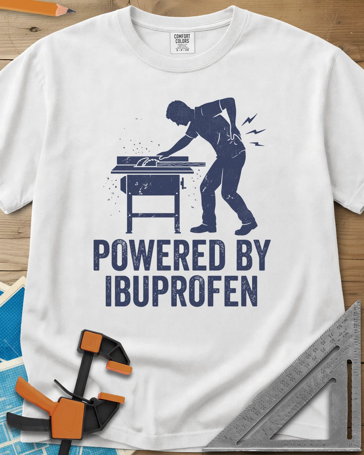 Powered By Ibuprofen heavyweight tee in White, a man at a table saw with a hand on his sore back
