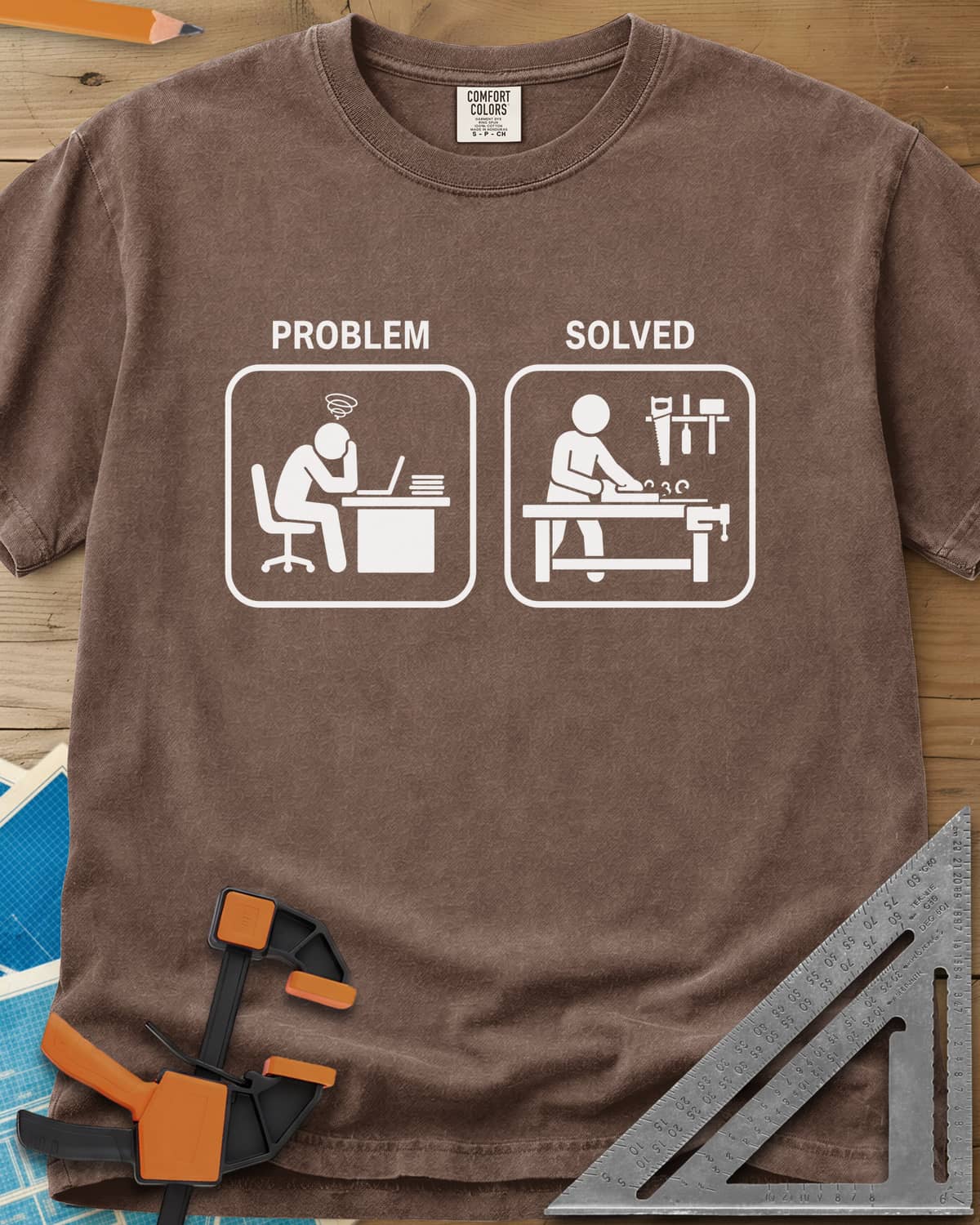 Problem Solved heavyweight tee in Espresso, two pictogram panels, a stressed desk worker and a woodworker planing