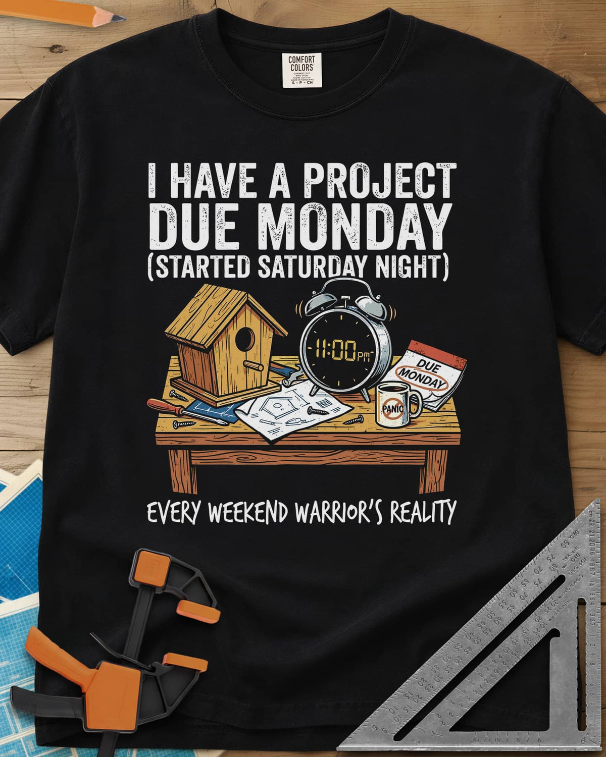 Project Due Monday heavyweight tee in Black, unfinished birdhouse on a bench with an 11 PM alarm clock and plans