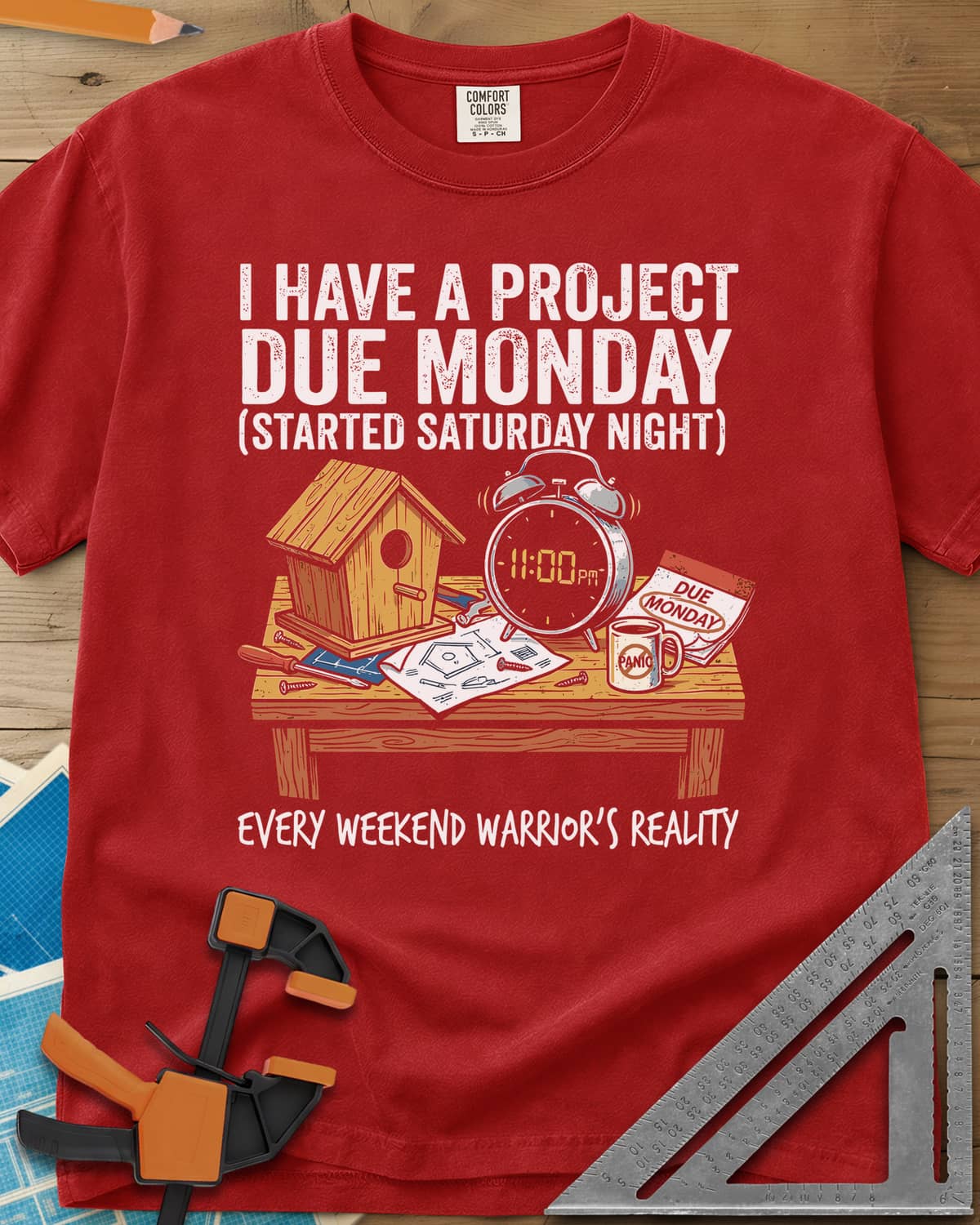 Project Due Monday heavyweight tee in Red, unfinished birdhouse on a bench with an 11 PM alarm clock and plans