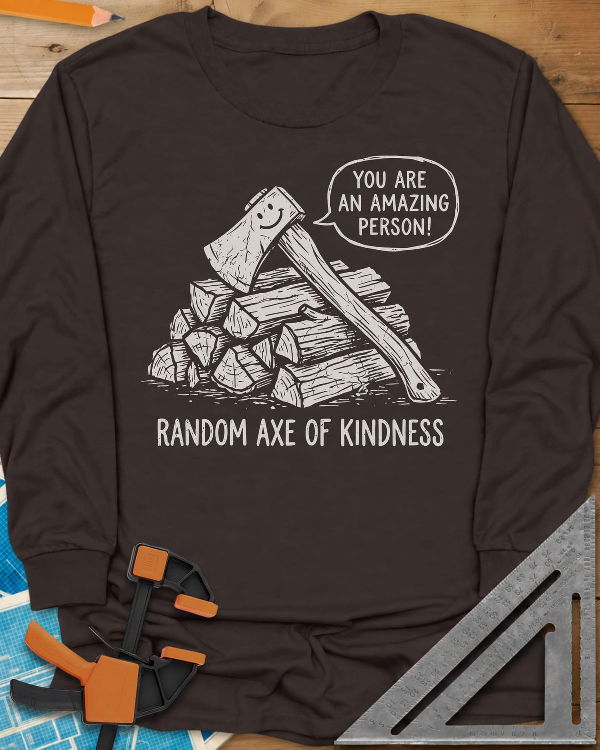 Random Axe of Kindness long sleeve shirt in Dark Chocolate, a smiling axe on a woodpile with an encouraging speech bubble