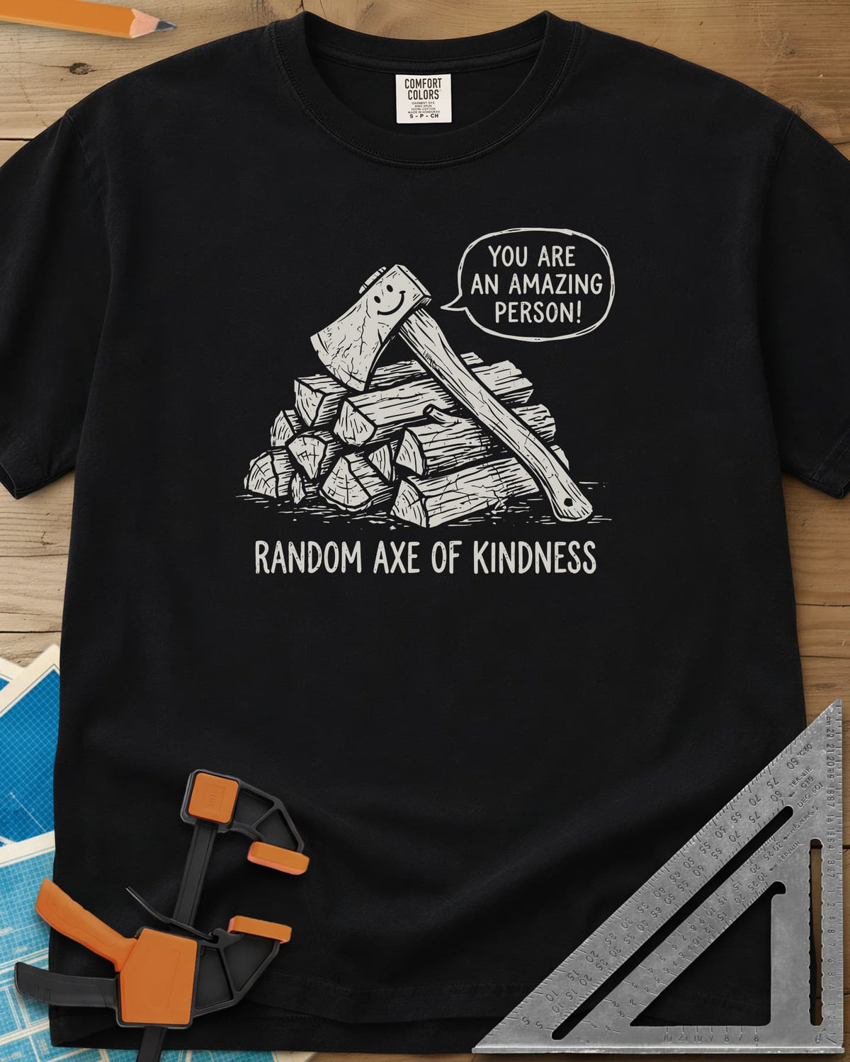 Random Axe of Kindness heavyweight tee in Black, a smiling axe on a woodpile with an encouraging speech bubble