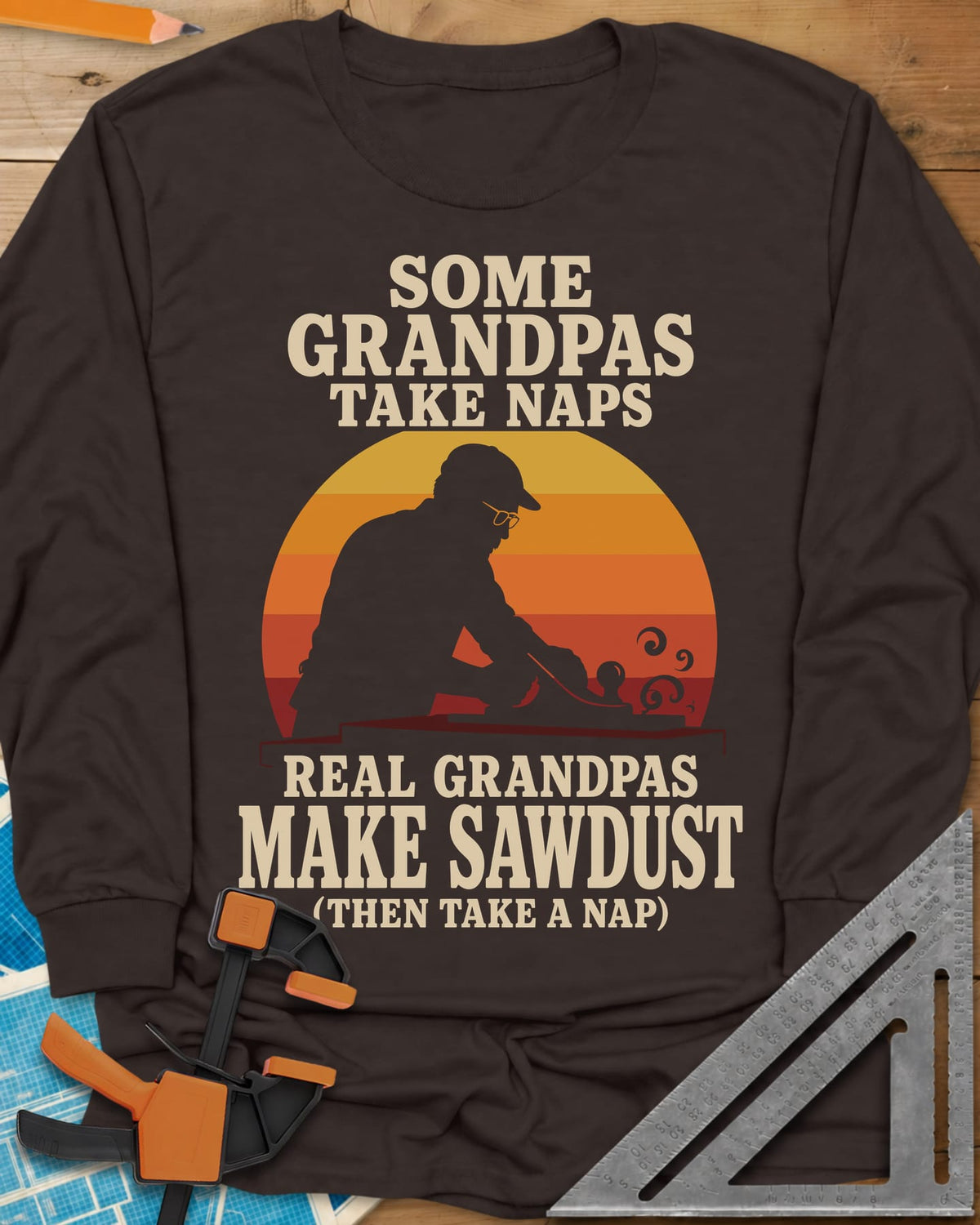 Real Grandpas Make Sawdust long sleeve shirt in Dark Chocolate, striped sunset circle behind a cap-wearing grandpa planing a